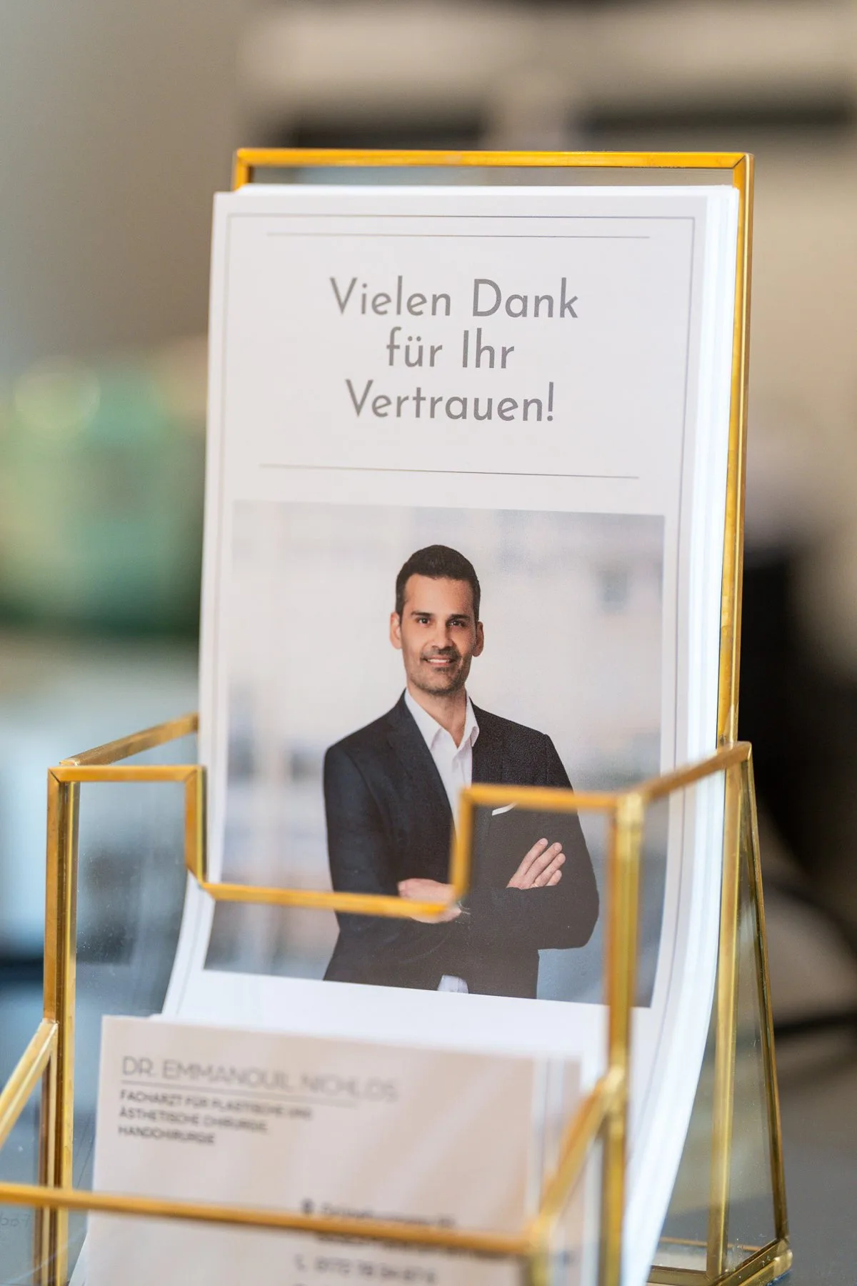 Flyer „Vielen Dank für Ihr Vertrauen!“ mit Dr. Nichlos am Empfang der Praxis in Frankfurt